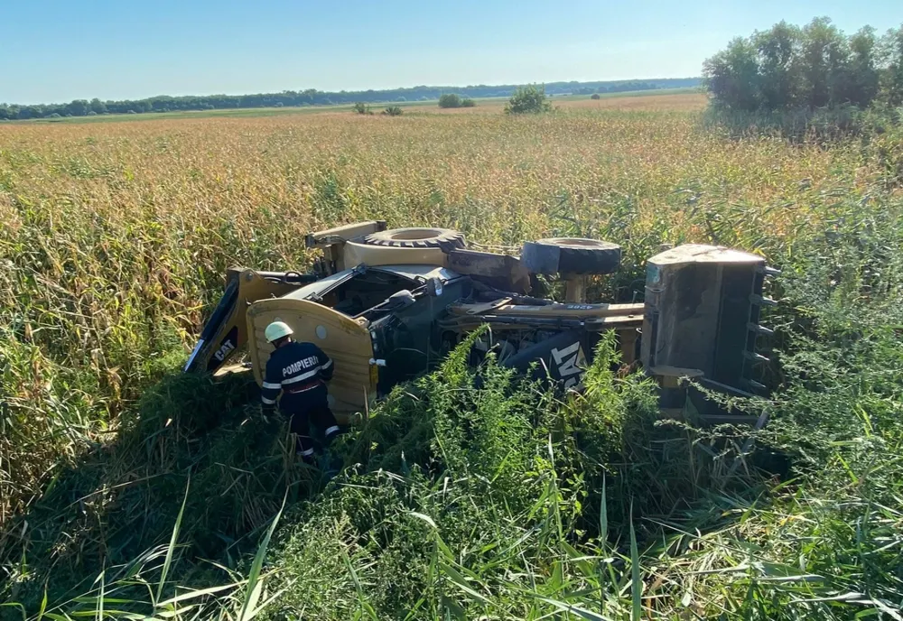 FOTO  Buldoexcavator răsturnat pe drumurile din Tulcea. Doi răniți